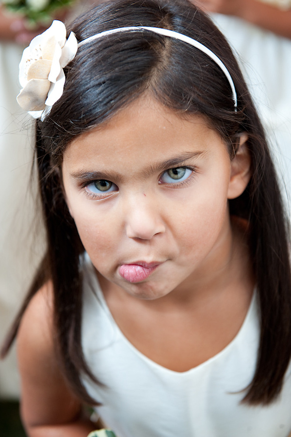 cute flower girl wearing a white floral headband making a funny face - photo by Houston based wedding photographer Adam Nyholt 